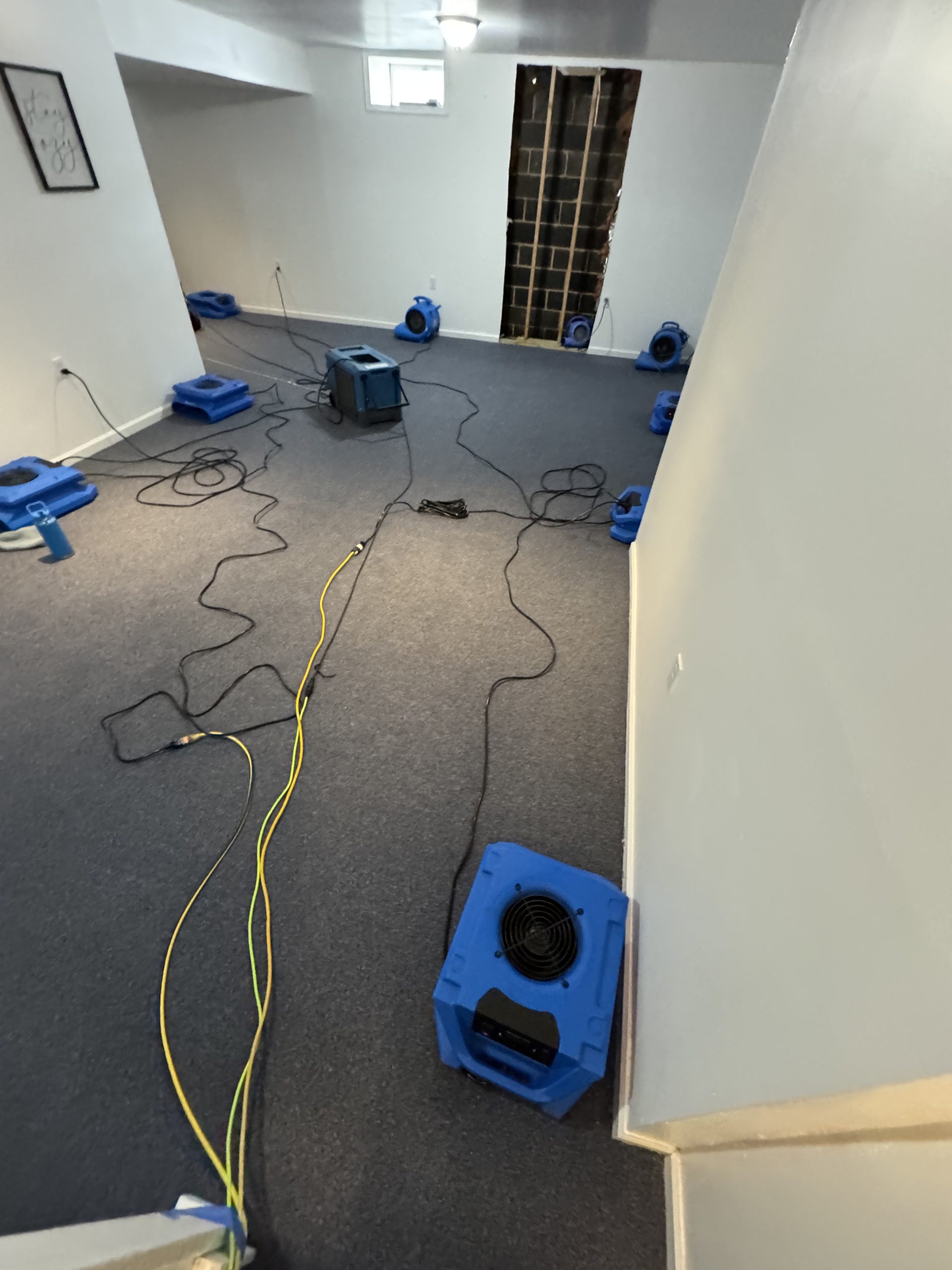 Emergency air movers drying carpeted room after water intrusion